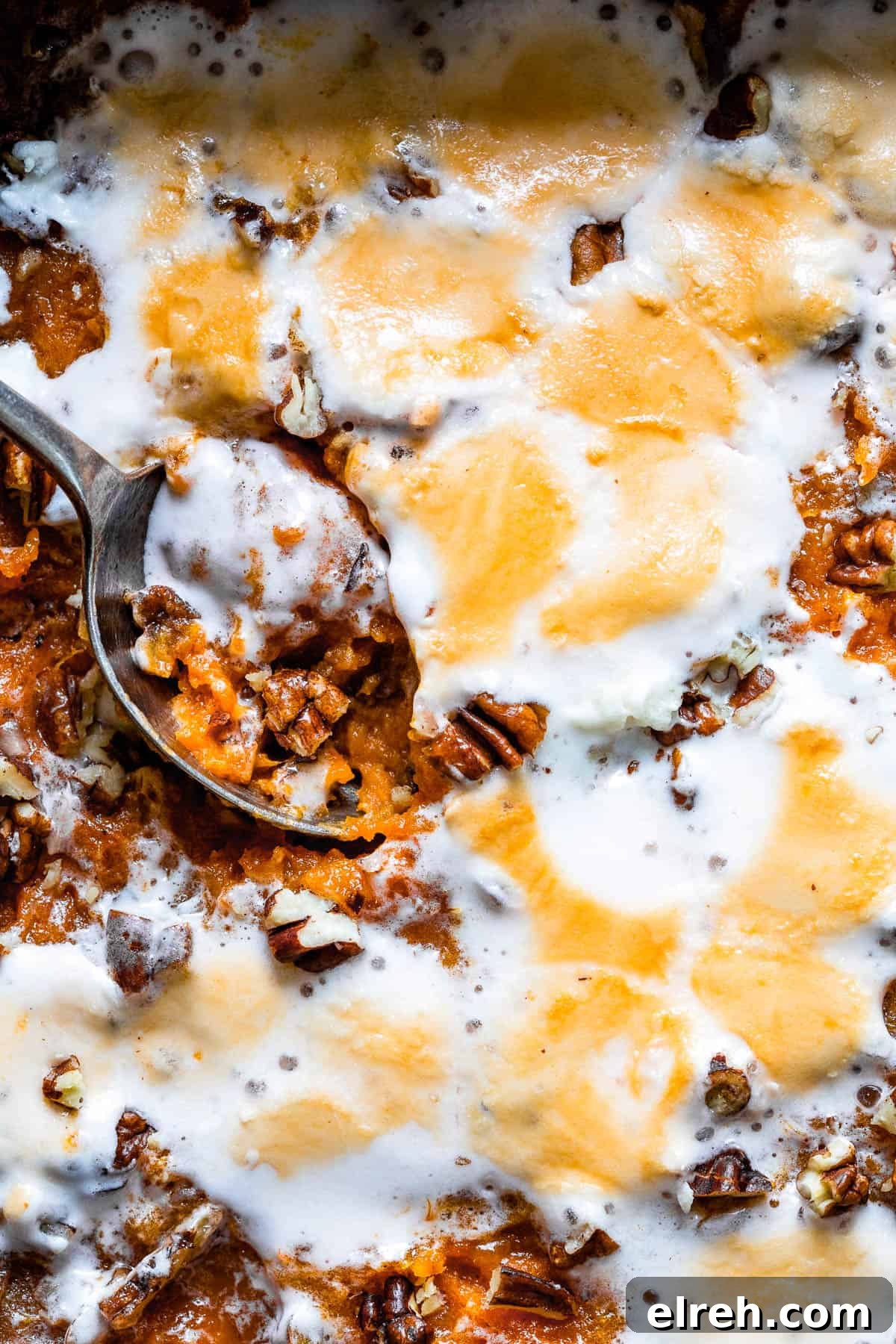 Baked sweet potato casserole with marshmallows and pecans.