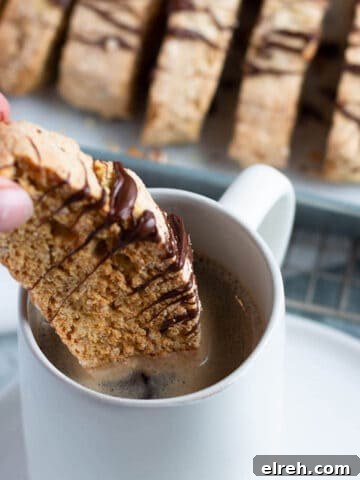 Sourdough almond biscotti being dipped in a cup of coffee.