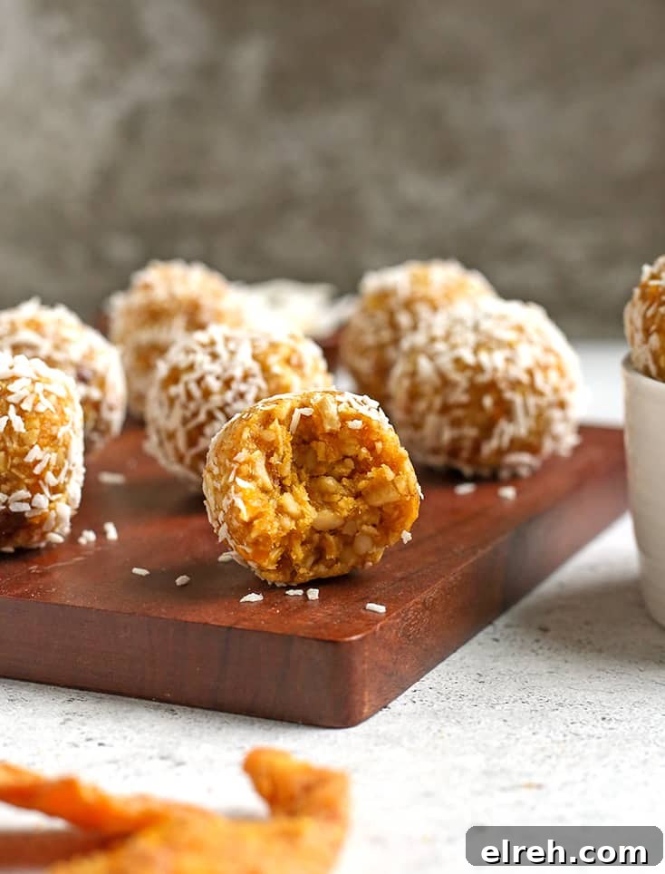 paleo vegan mango coconut bites sitting on a cutting board, one with a bite taken out