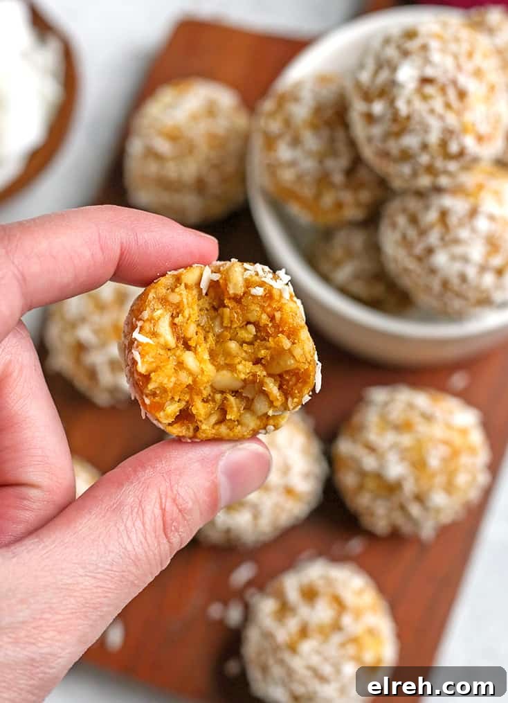 hand holding a paleo mango coconut bite with a bite taken out 