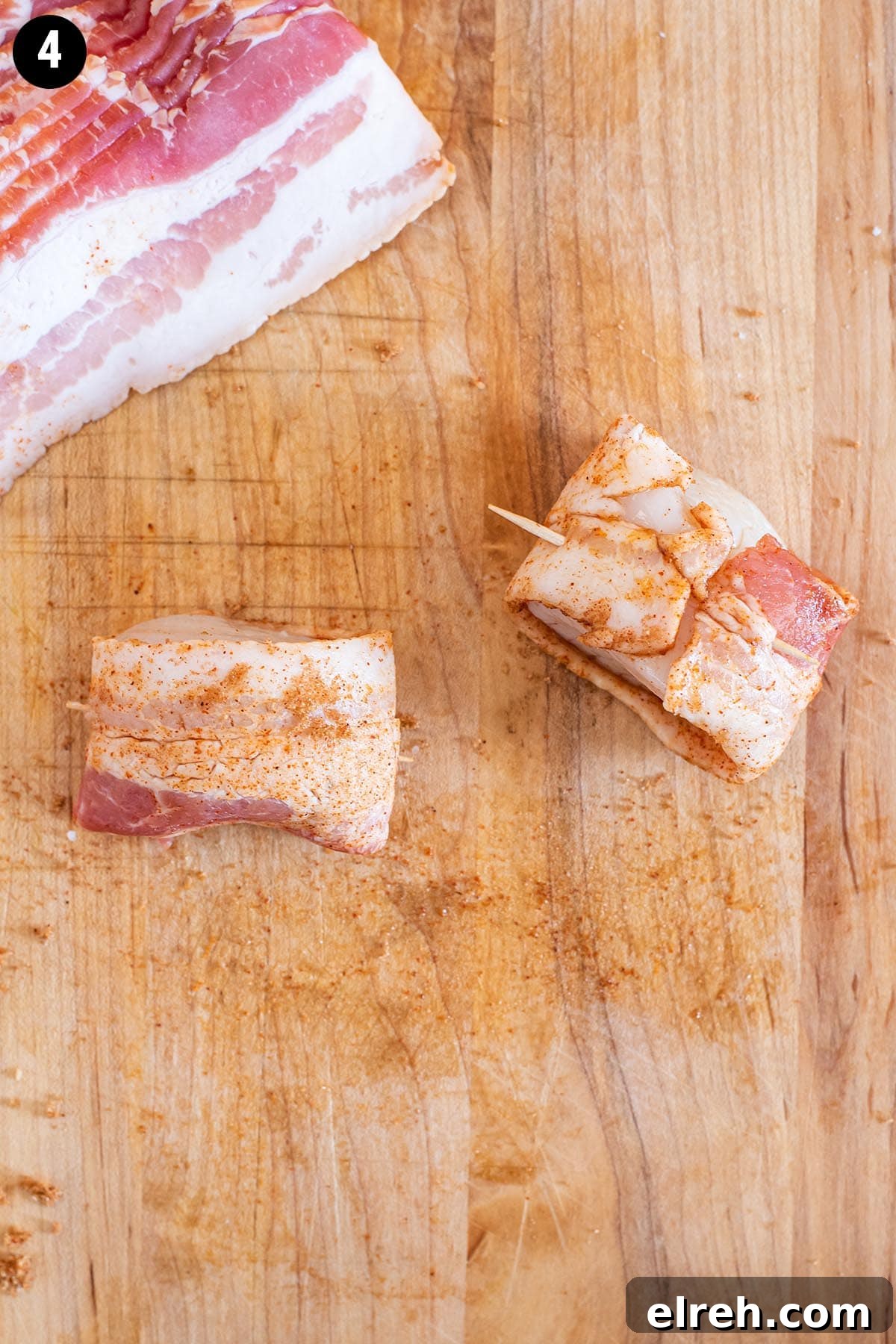 Sweet and Smoky Bacon Wrapped Scallops 7 Raw scallops wrapped in uncooked bacon on a wooden cutting board.