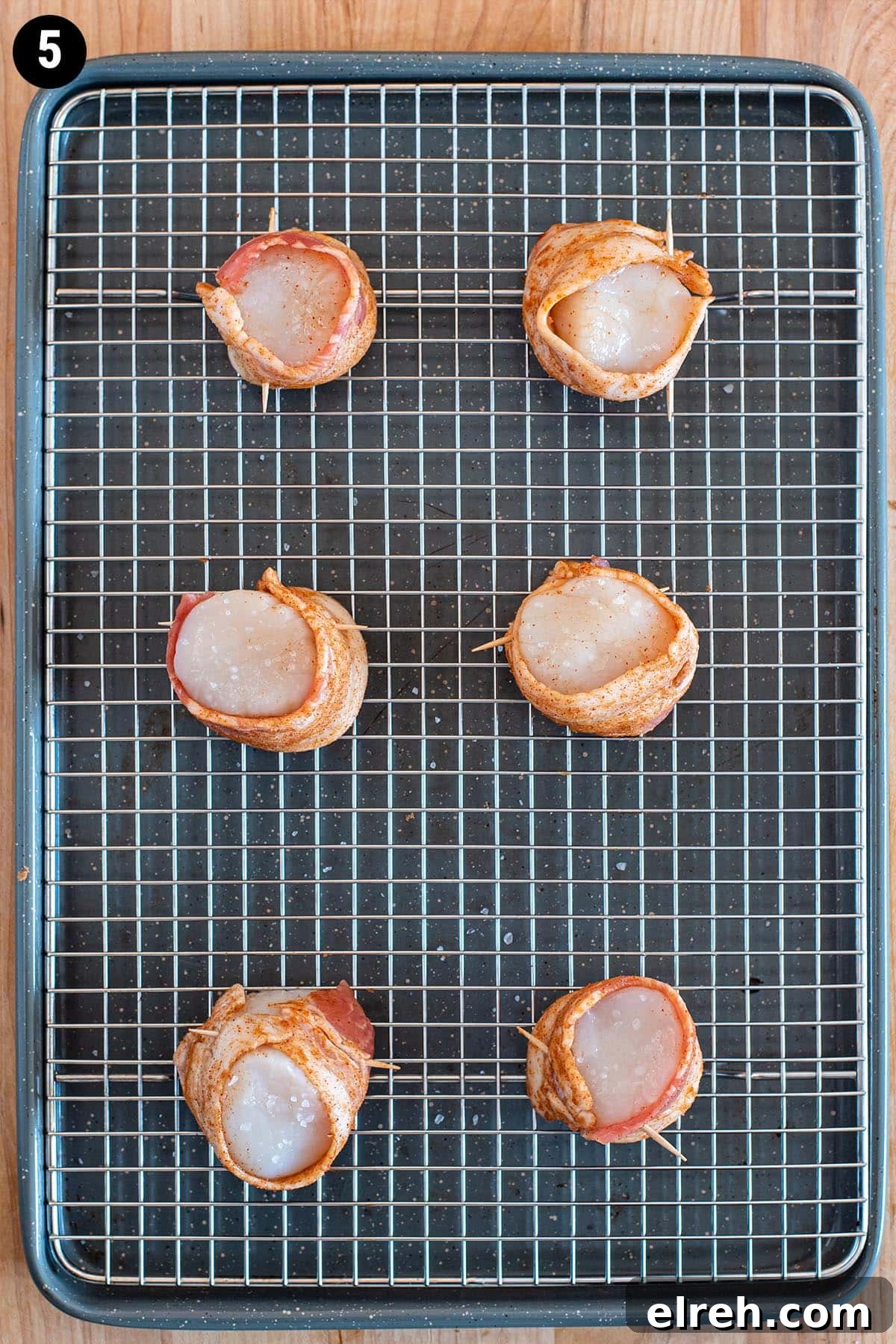 Sweet and Smoky Bacon Wrapped Scallops 8 Raw scallops wrapped in uncooked bacon on a wire rack lined backing sheet.