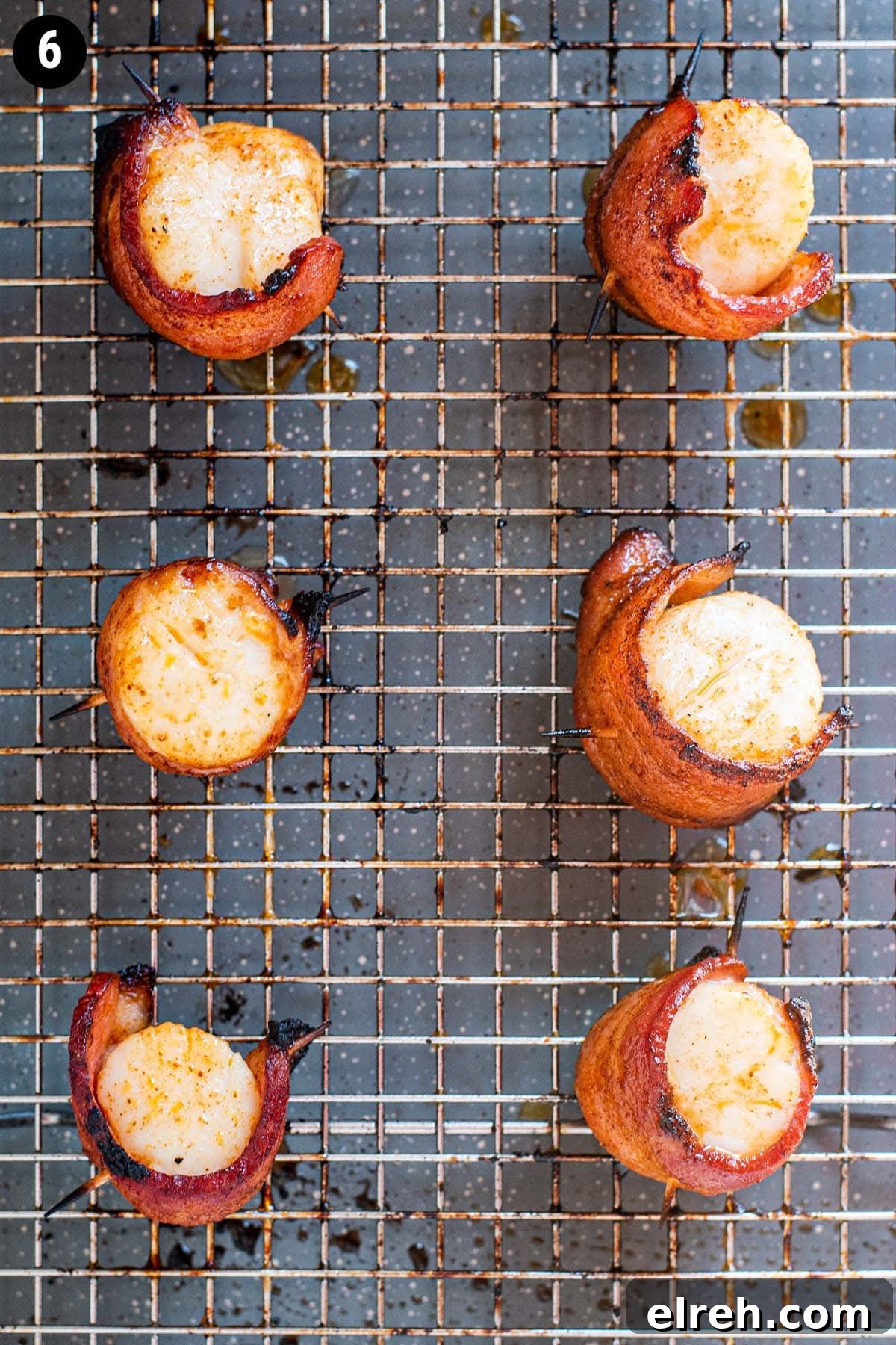Sweet and Smoky Bacon Wrapped Scallops 9 Fully cooked golden brown scallops wrapped in bacon on a wire rack stacked on a baking sheet.