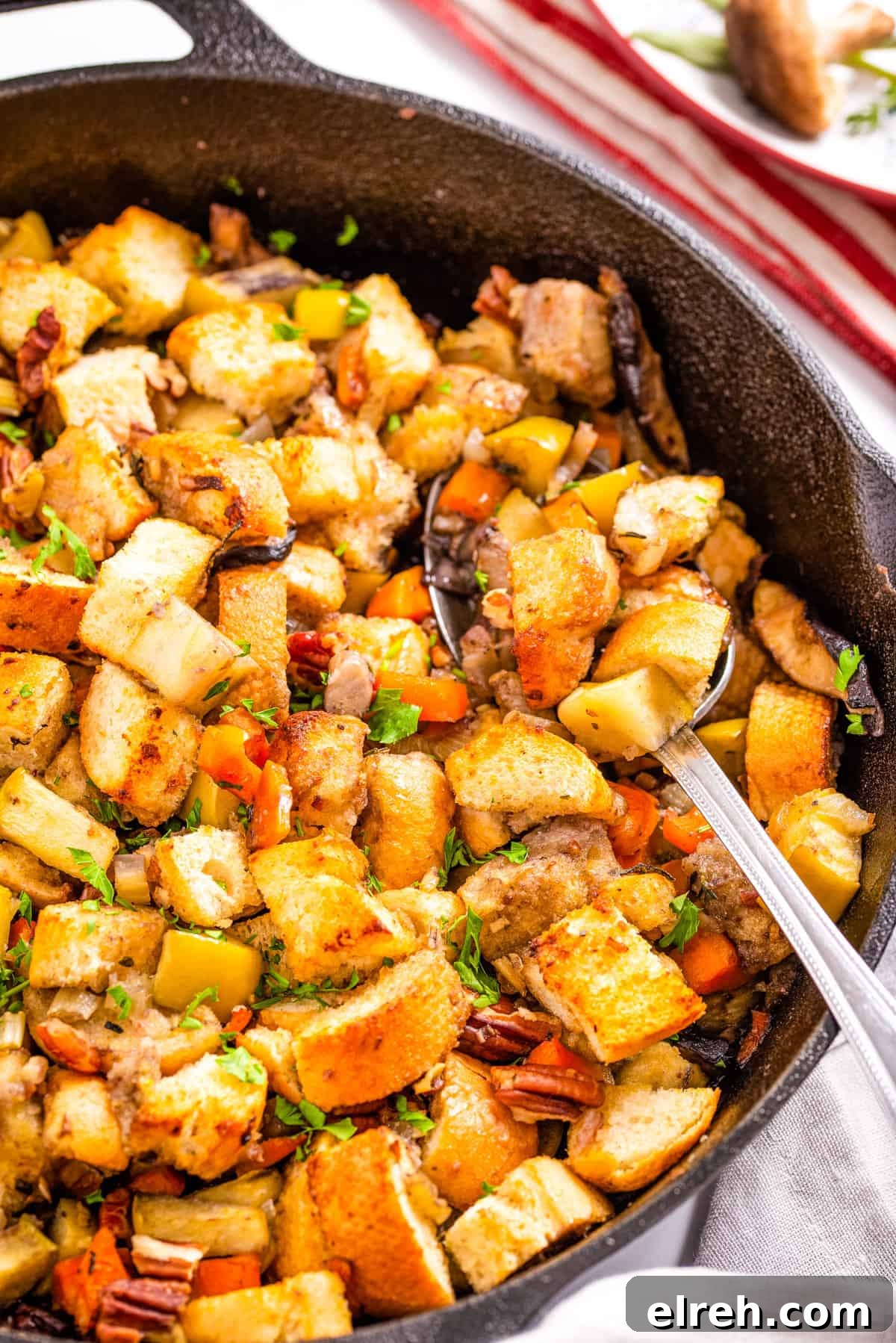 Classic Vegan Stuffing with Herbs and Cranberries 2 Close up of vegan stuffing in skillet with a spoon in it.