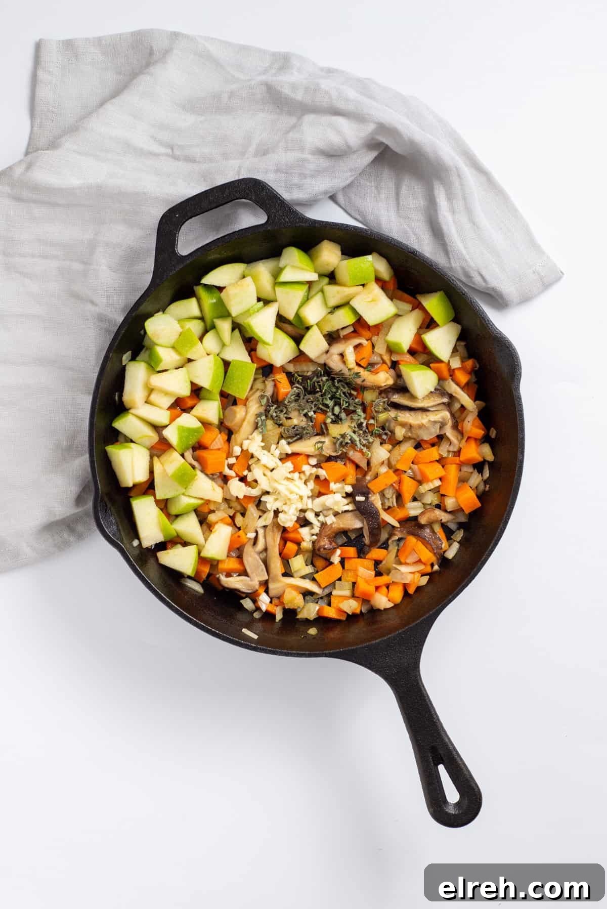 Classic Vegan Stuffing with Herbs and Cranberries 6 Overhead view of skillet with apples, herbs added in.