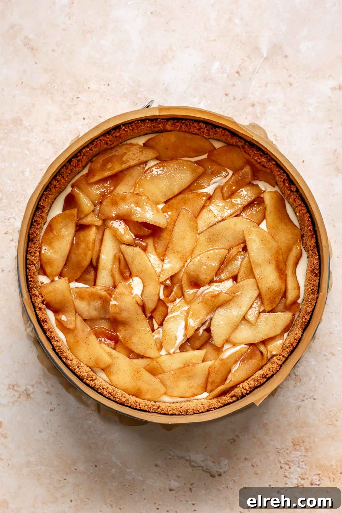 Apple Crumble Cheesecake with Cinnamon Streusel Recipe 16 Apple pie filling on top of cheesecake batter in a pan.