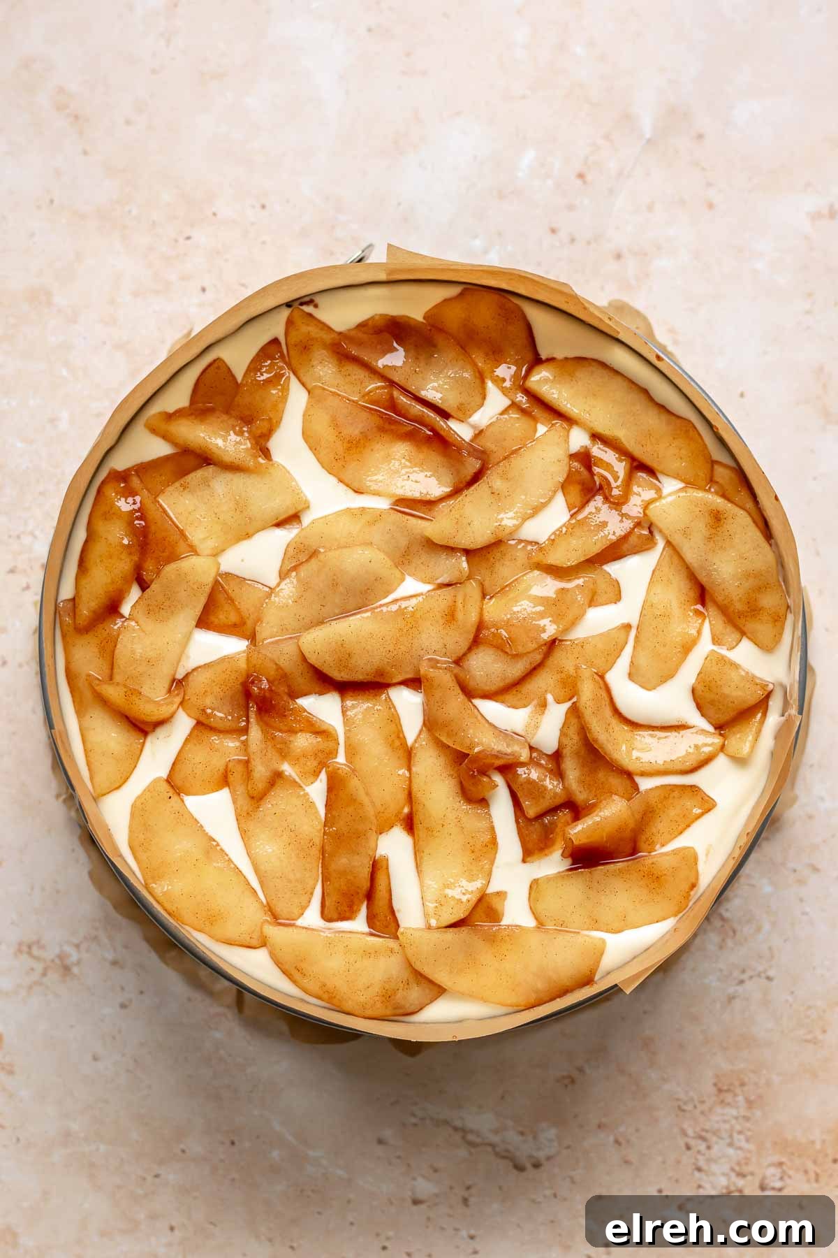 Apple Crumble Cheesecake with Cinnamon Streusel Recipe 18 Apple pie filling on top of cheesecake batter in a pan.