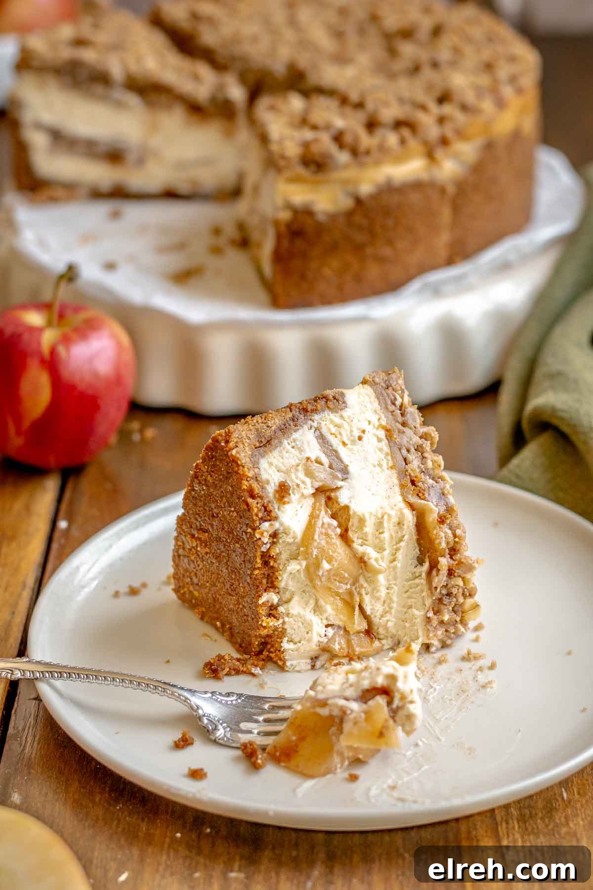 Apple Crumble Cheesecake with Cinnamon Streusel Recipe 3 A piece of apple crisp cheesecake on a plate with bites removed.
