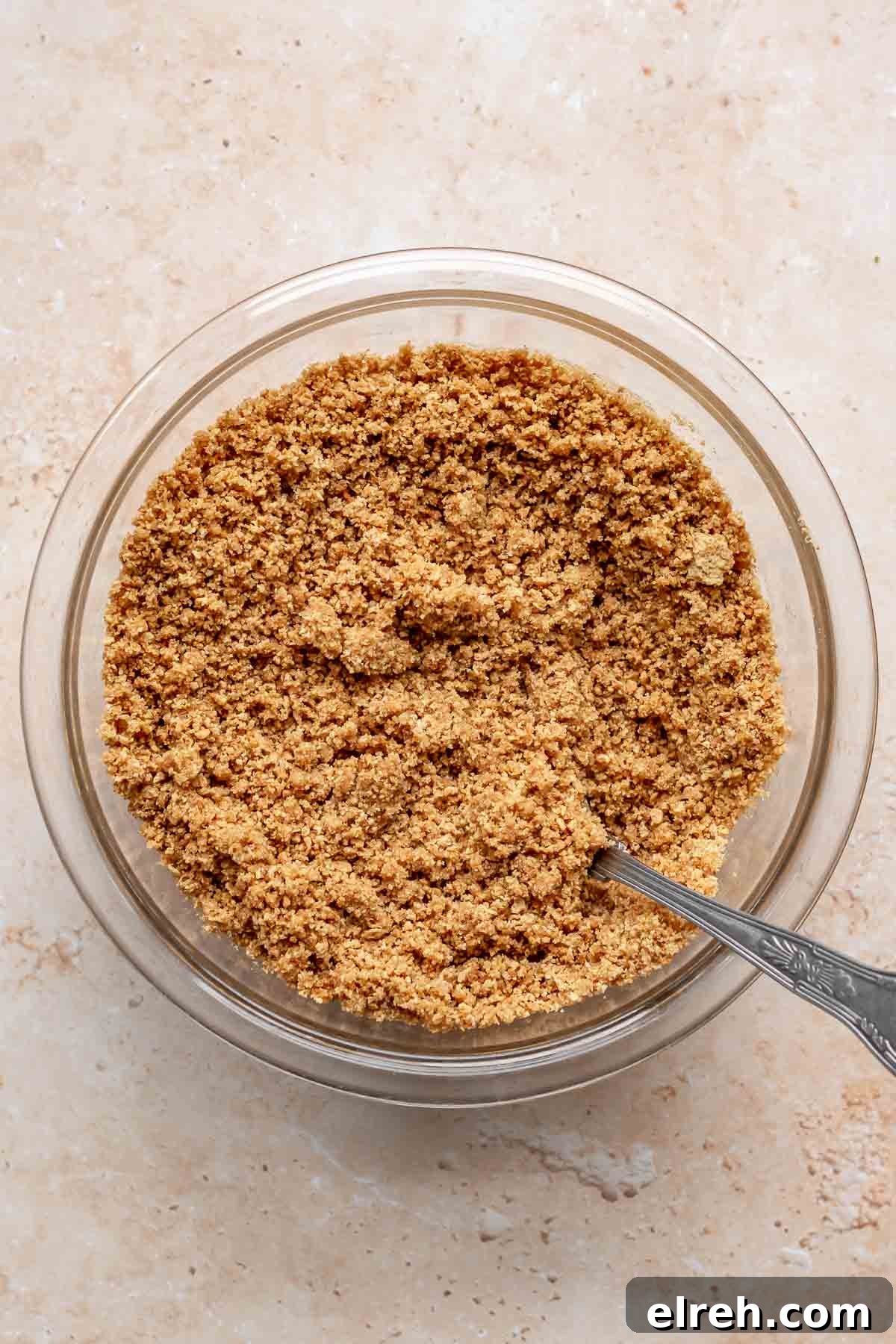 Apple Crumble Cheesecake with Cinnamon Streusel Recipe 8 Graham cracker crumbs mixed in a bowl with a fork.