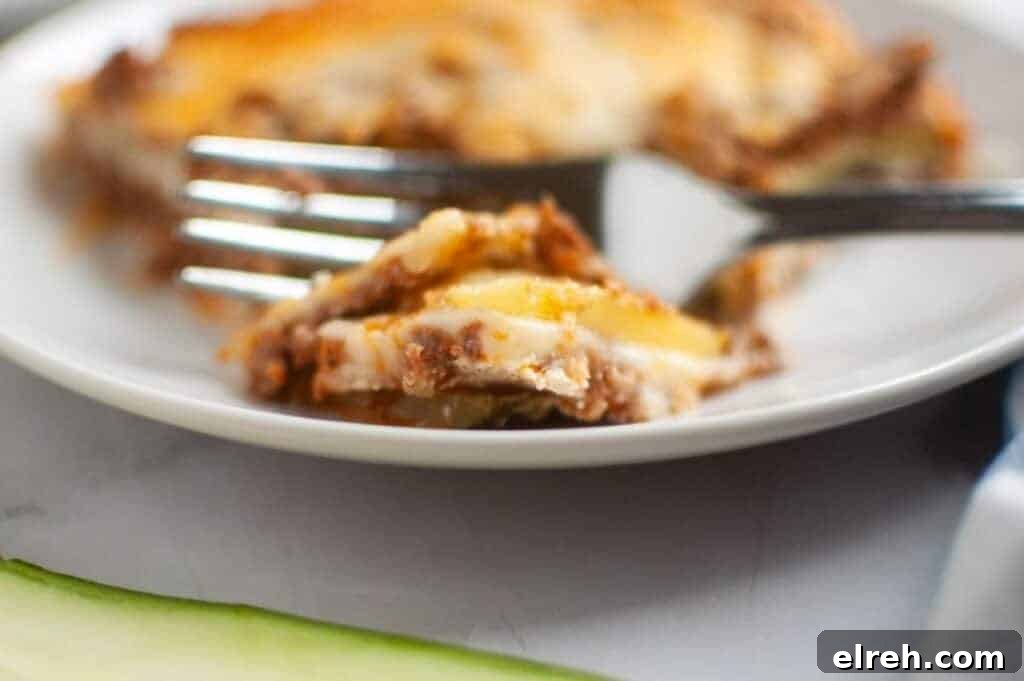 A close-up, slightly high-angle view of Zucchini Lasagna squares arranged on a dark gray baking sheet, each topped with a glossy, light brown apple filling and a generous sprinkle of light brown crumb topping.