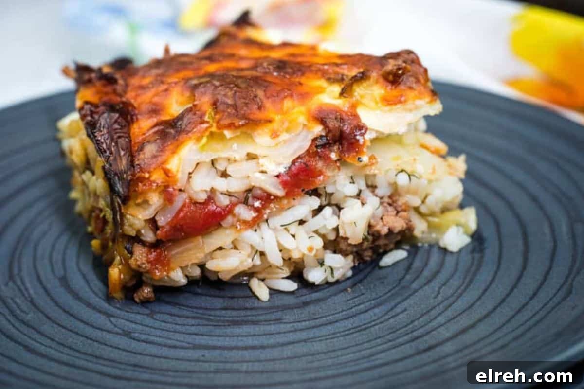 A slice of layered cabbage roll casserole served on a dark plate.