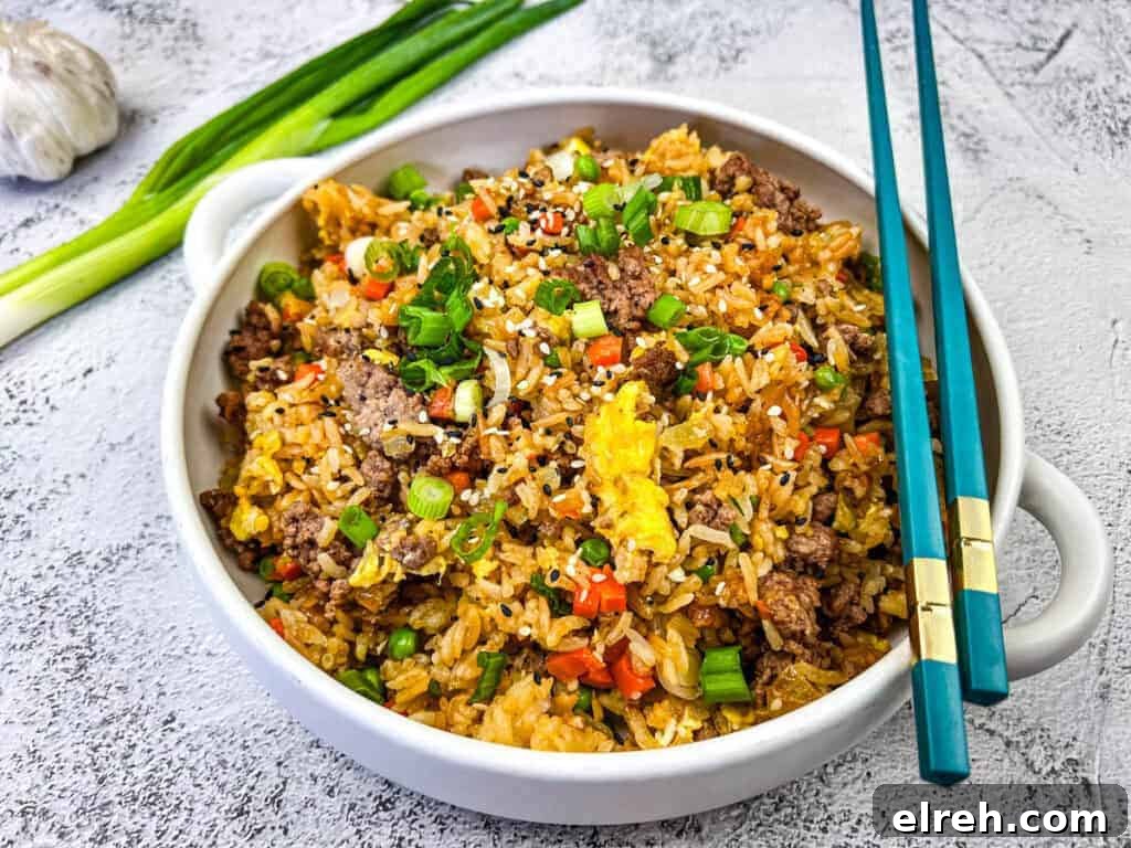 Ground Beef Fried Rice served in a white bowl with blue chopstick on top.