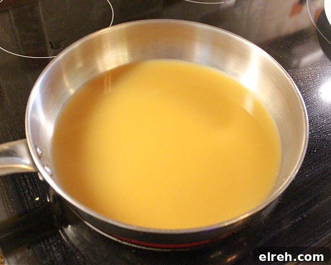 Apple Juice Glazed Chicken Thighs Recipe 4 Apple juice in a steel pan on a stove.
