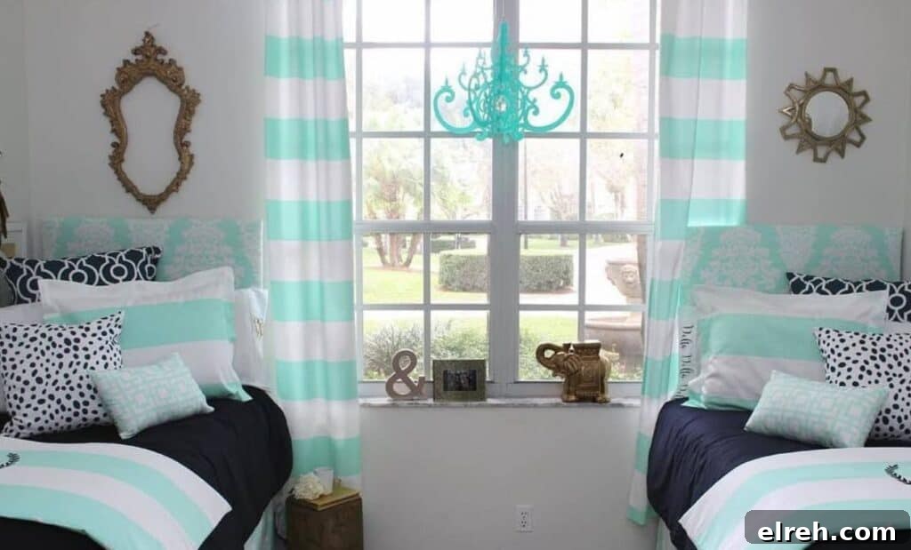 A bedroom with two twin beds featuring teal and white bedding, striped teal and white curtains, a large window in the center, and various decor items including pillows, frames, and a chandelier.