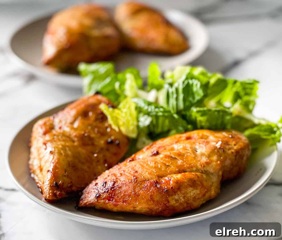 How to Cook Frozen Chicken Breasts in an Air Fryer 11 Juicy chicken breasts on a plate with a side of green salad.