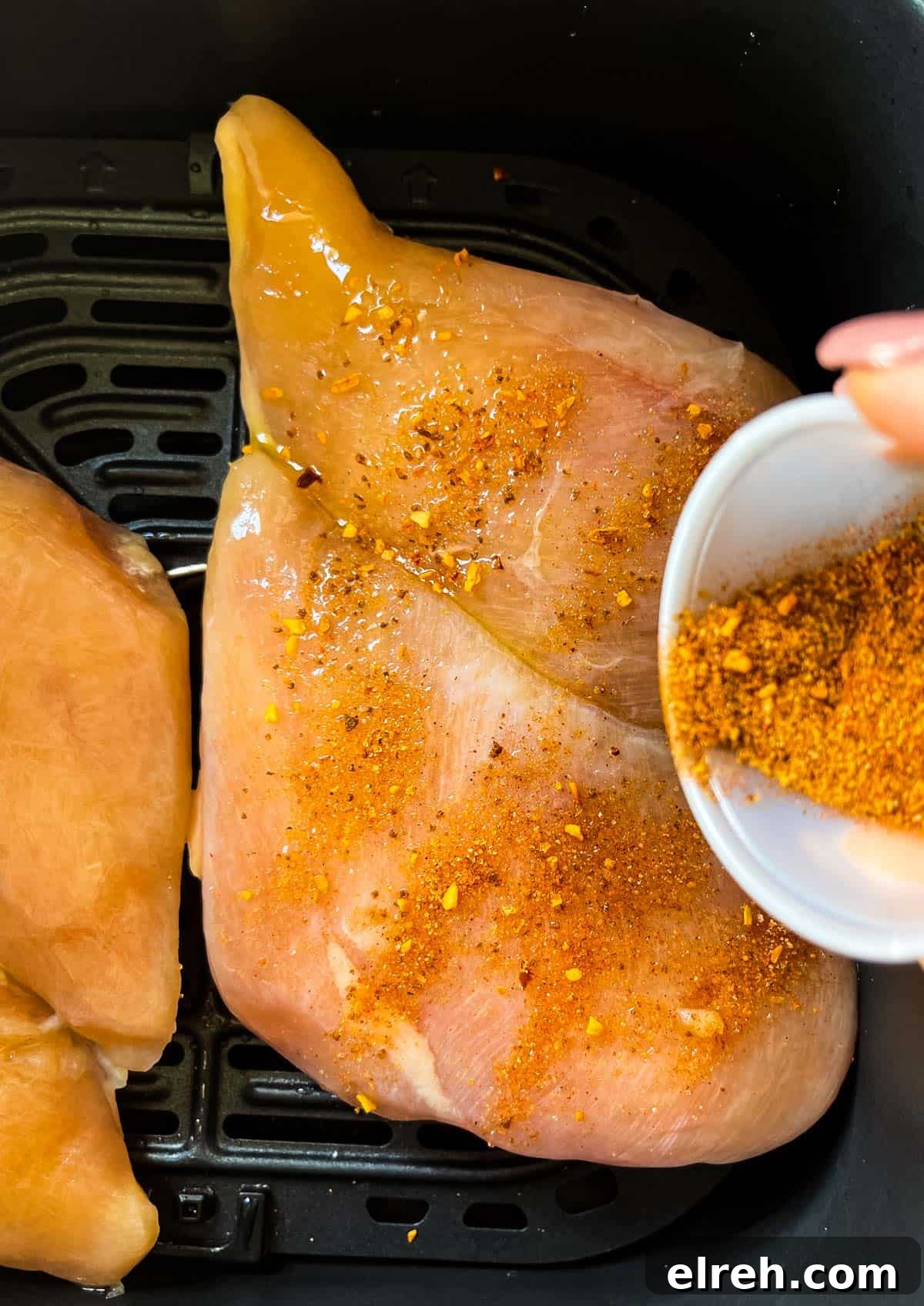 How to Cook Frozen Chicken Breasts in an Air Fryer 5 Dry rub being sprinkled on top of the frozen chicken.