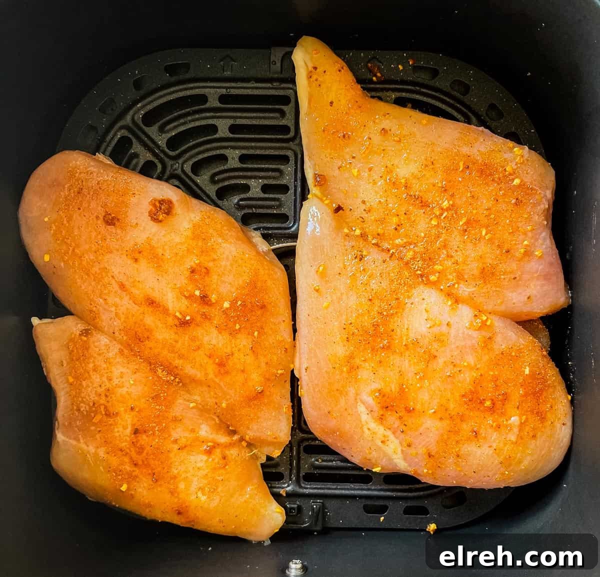 How to Cook Frozen Chicken Breasts in an Air Fryer 6 Frozen chicken breasts covered in rub and placed in the air fryer basket.