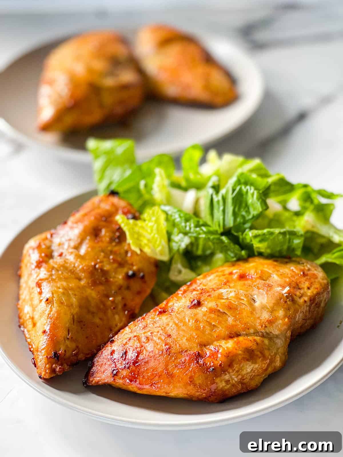 How to Cook Frozen Chicken Breasts in an Air Fryer 9 Air fried chicken breasts on a plate with a green salad.
