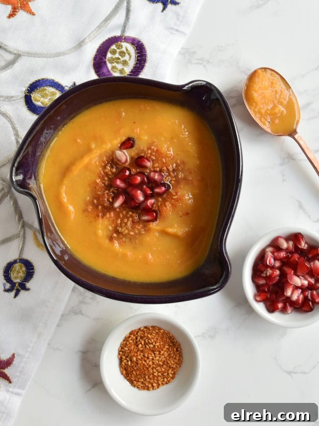 Soup in purple bowl with copper spoon and dukkah and arils.