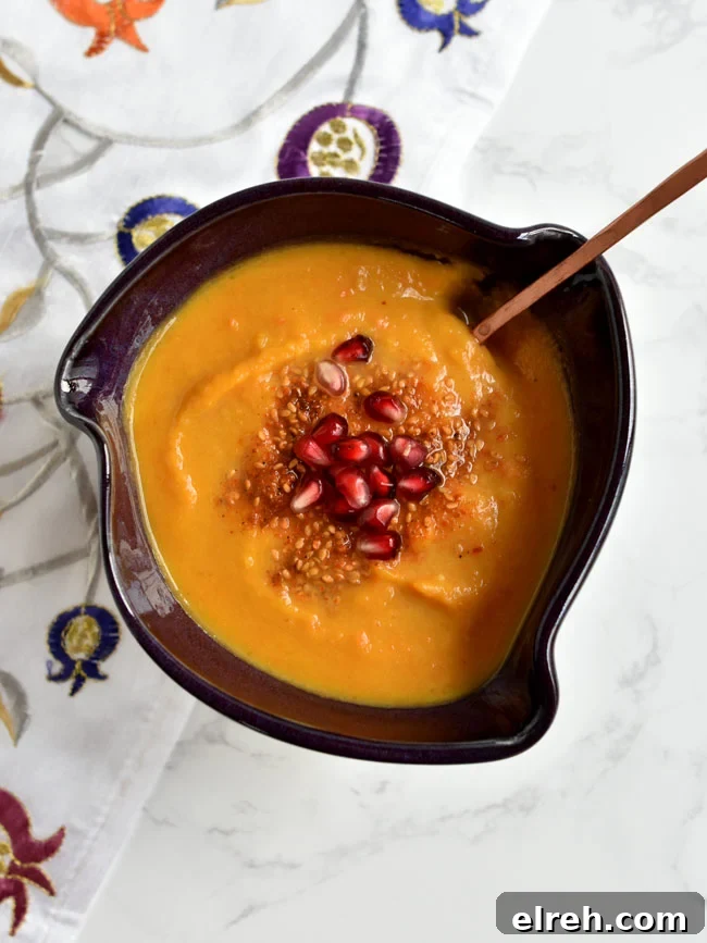 Squash soup in purple bowl with copper spoon.