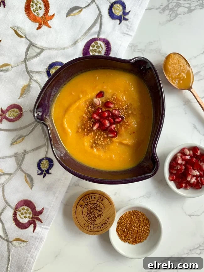 Squash soup with dukkah and pomegranate arils and copper spoon.