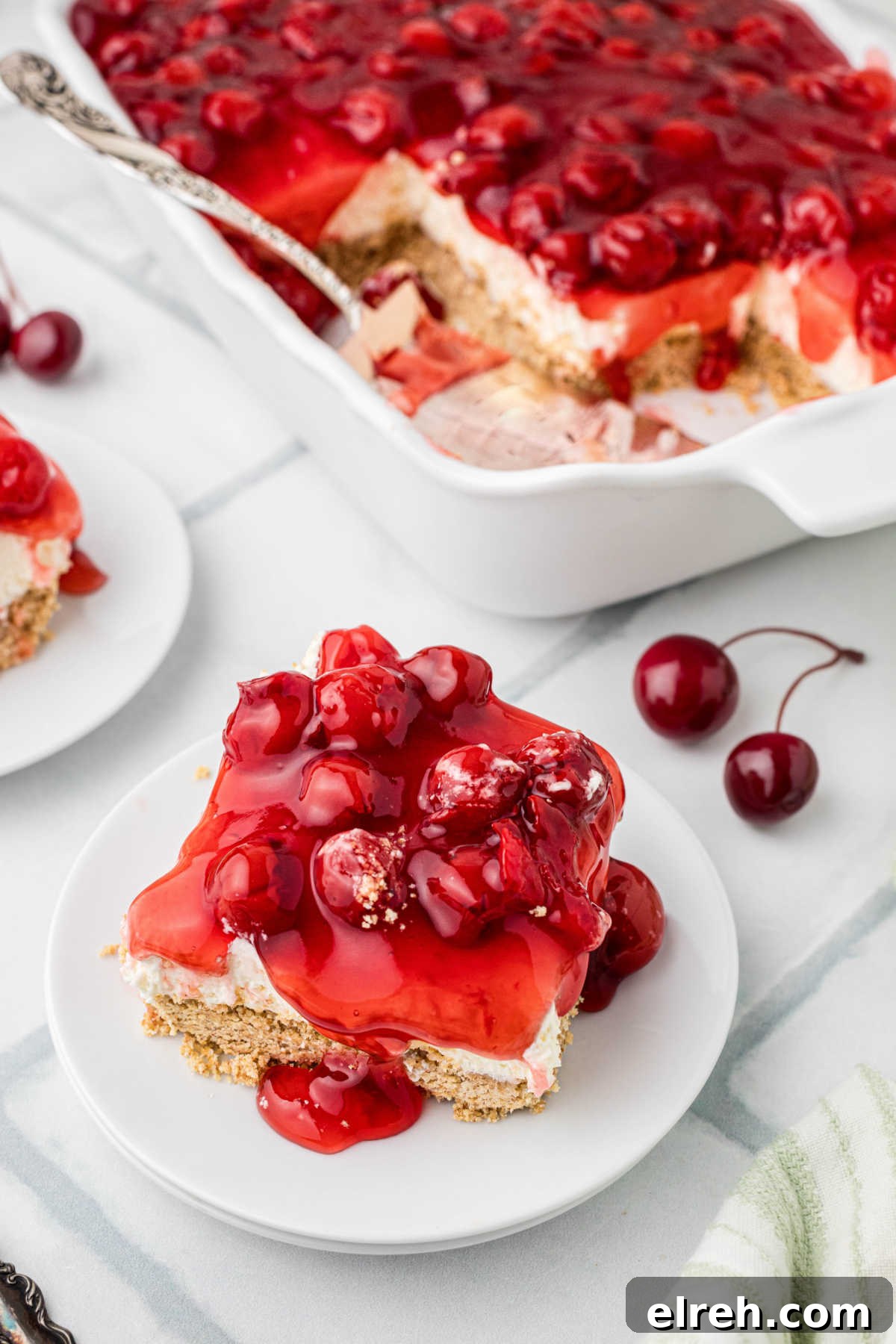 An old fashioned cherry delight, on a plate in front of the full dish.