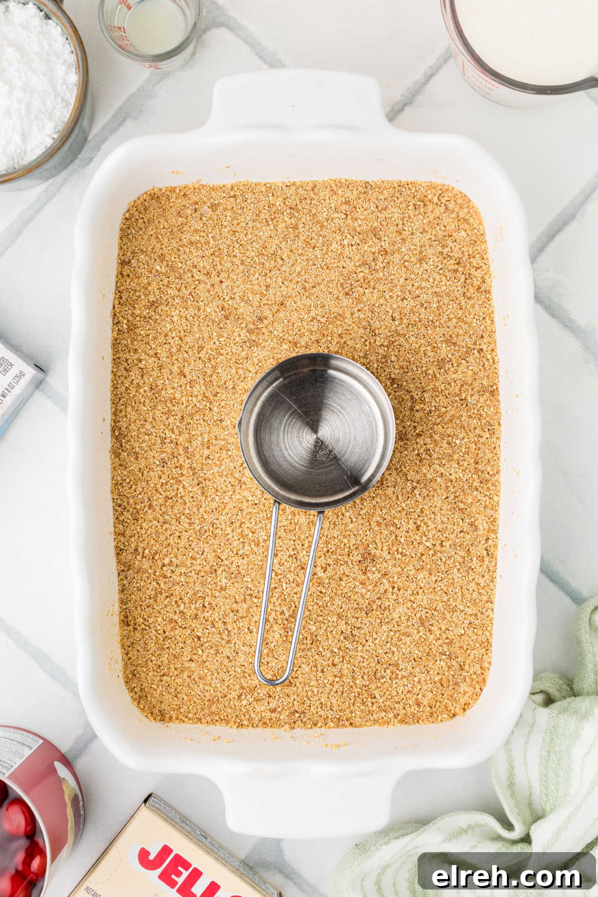 A crumb mixture being pressed into the bottom of a baking dish.