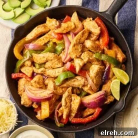 A pan filled with cooked chicken fajitas on a table, with side dishes around, ready to eat.