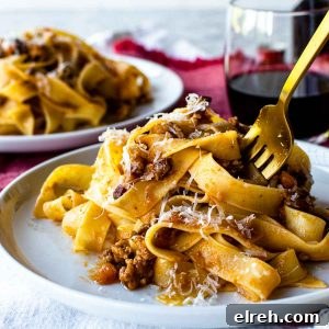 white plate with pasta on it and a gold fork in the pasta.