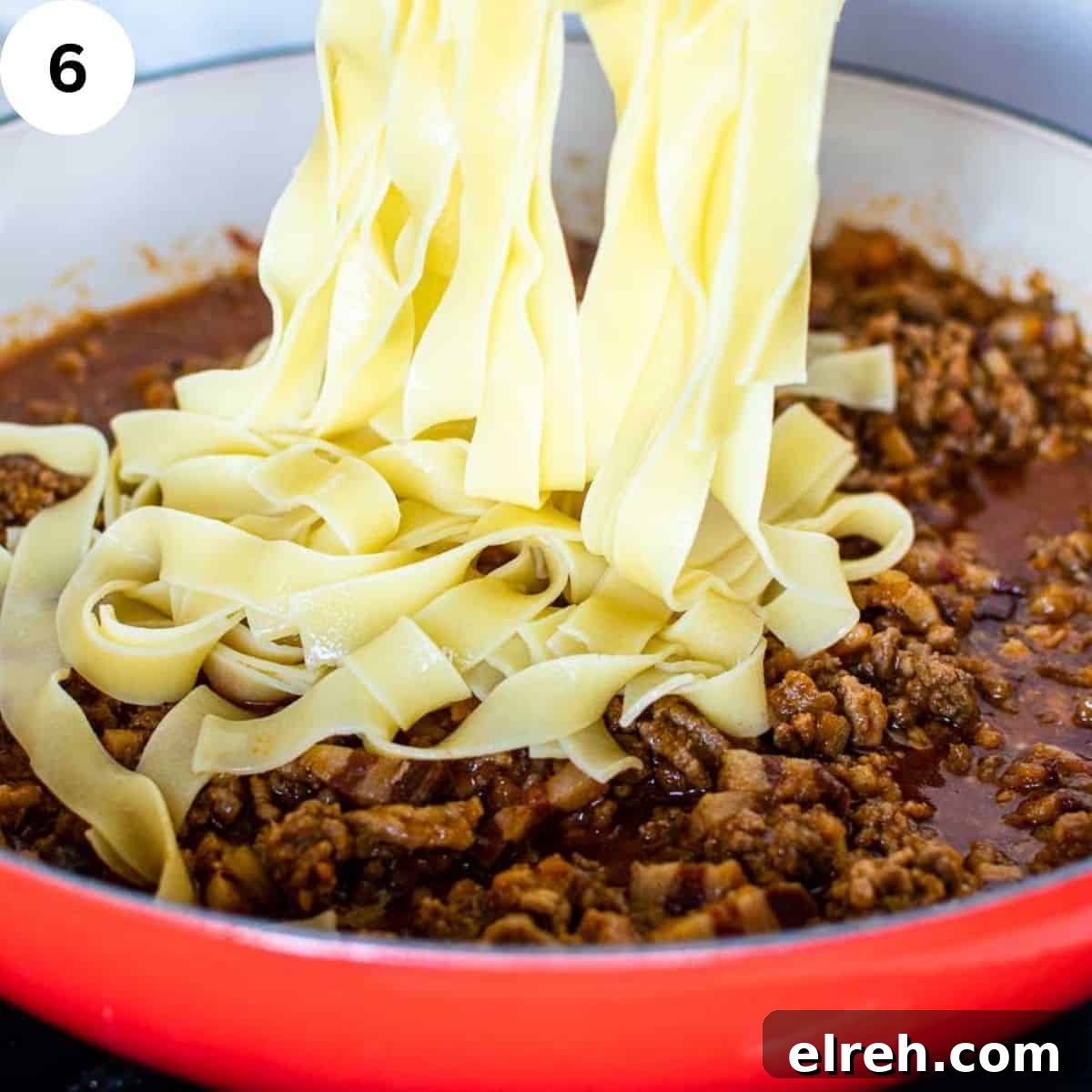 Authentic Tagliatelle with Bolognese Sauce Recipe 9 Tagliatelle being added to meat sauce in a round pan.