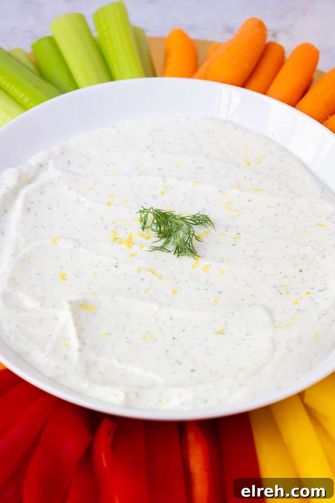 Creamy cottage cheese ranch dip on a serving platter with fresh veggies including red bell peppers and carrots.
