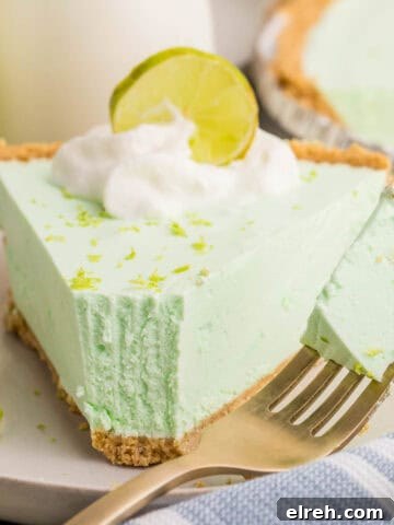 Close-up of a slice of key lime Jello pie with a bite on a fork beside it.