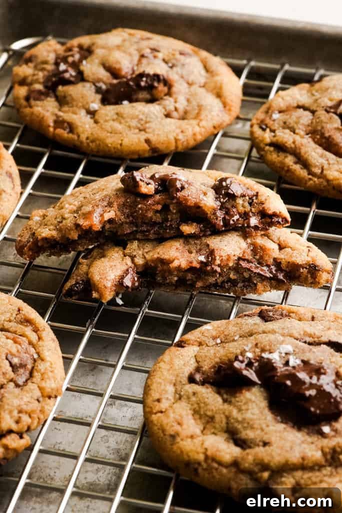 brown butter toffee and chocolate chip cookie split in half on a wired rack among more cookies.
