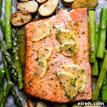 Baked salmon with honey garlic butter sauce and lemons on a baking tray