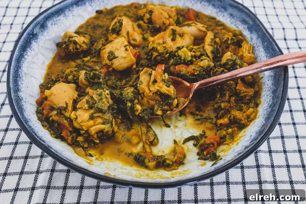 A bowl of chicken curry cooked with fenugreek leaves with a serving spoon