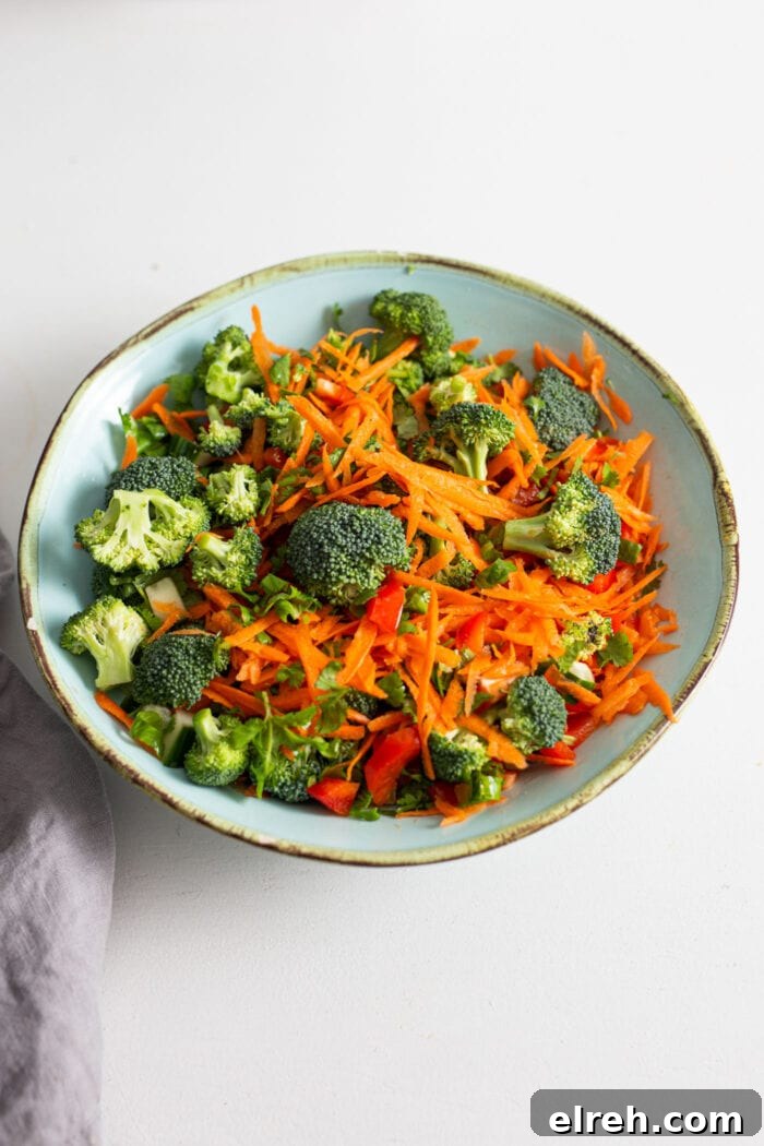 Bell pepper, cucumber, carrot, broccoli and cilantro mixed together in a bowl.
