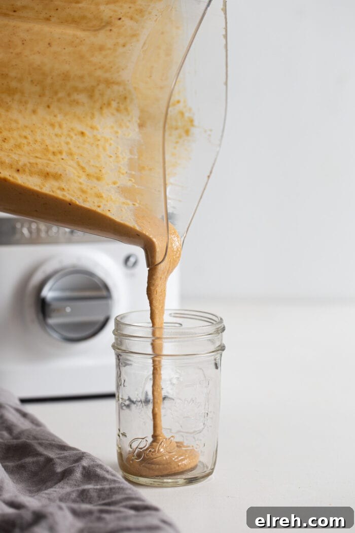 Blender pouring peanut sauce into a jar.