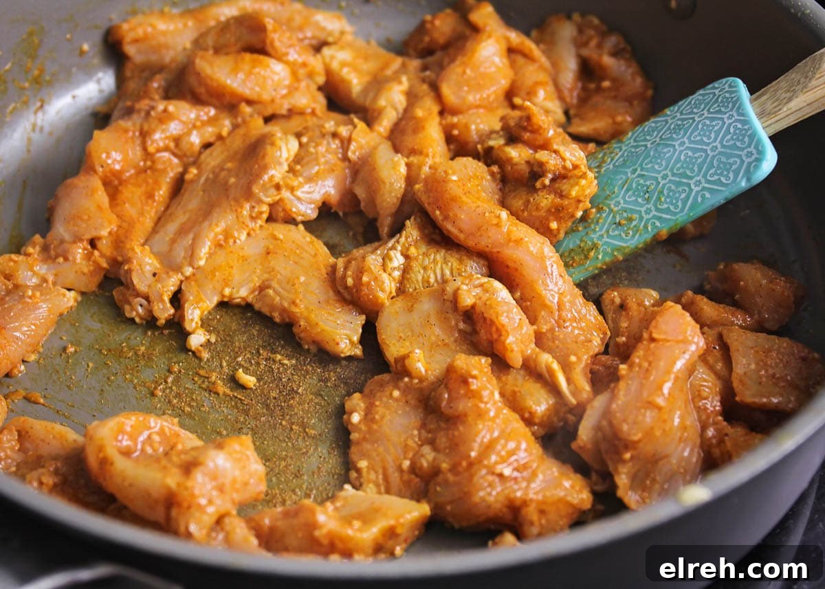 Seasoned chicken cooking in a skillet on the stove.
