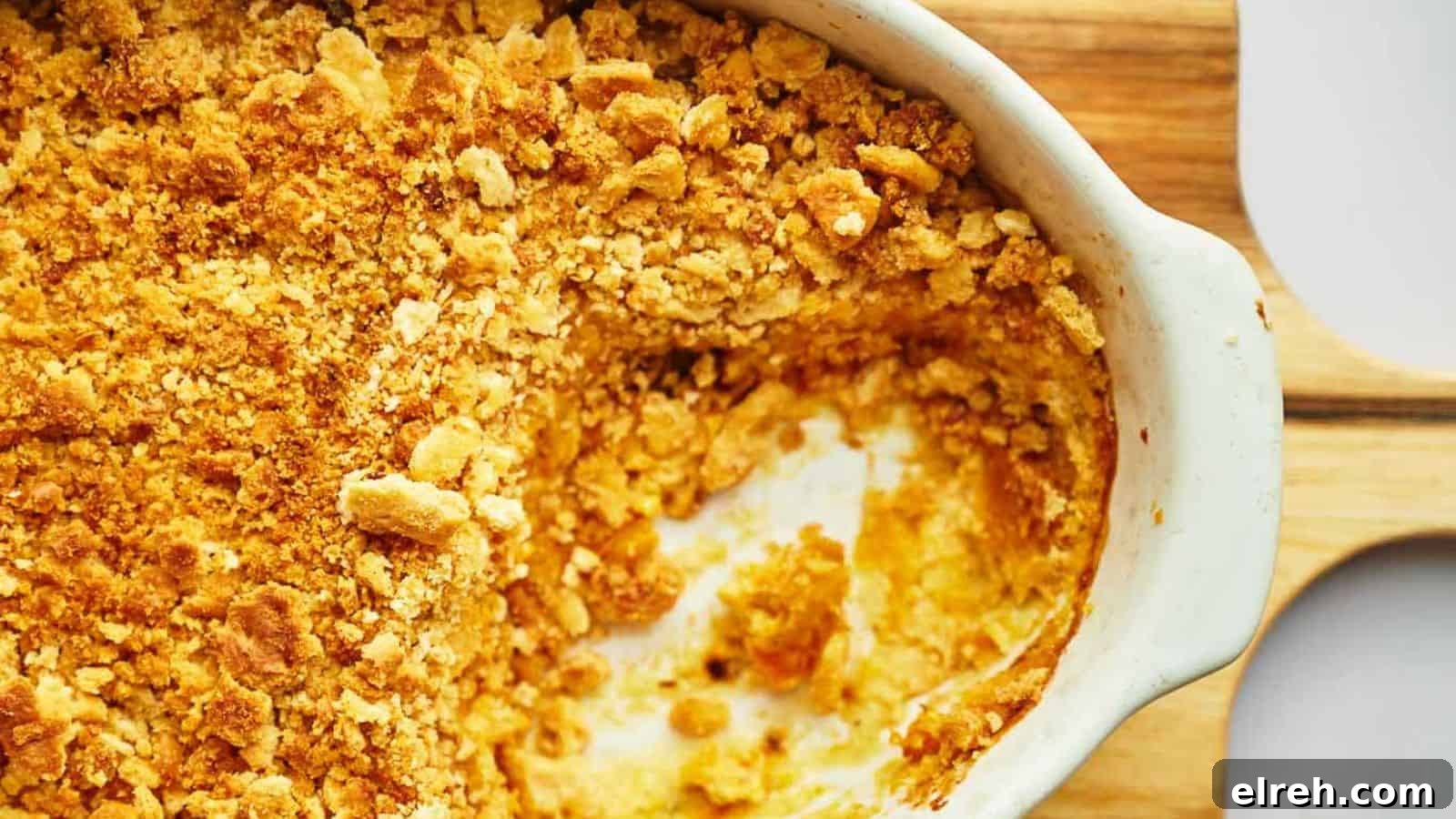 Squash casserole being served with a wooden serving spoon.