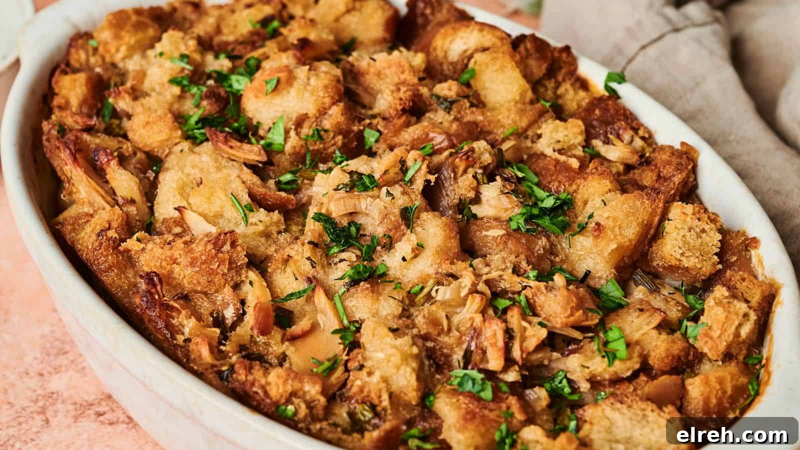 A golden brown Thanksgiving casserole of baked stuffing garnished with fresh herbs.