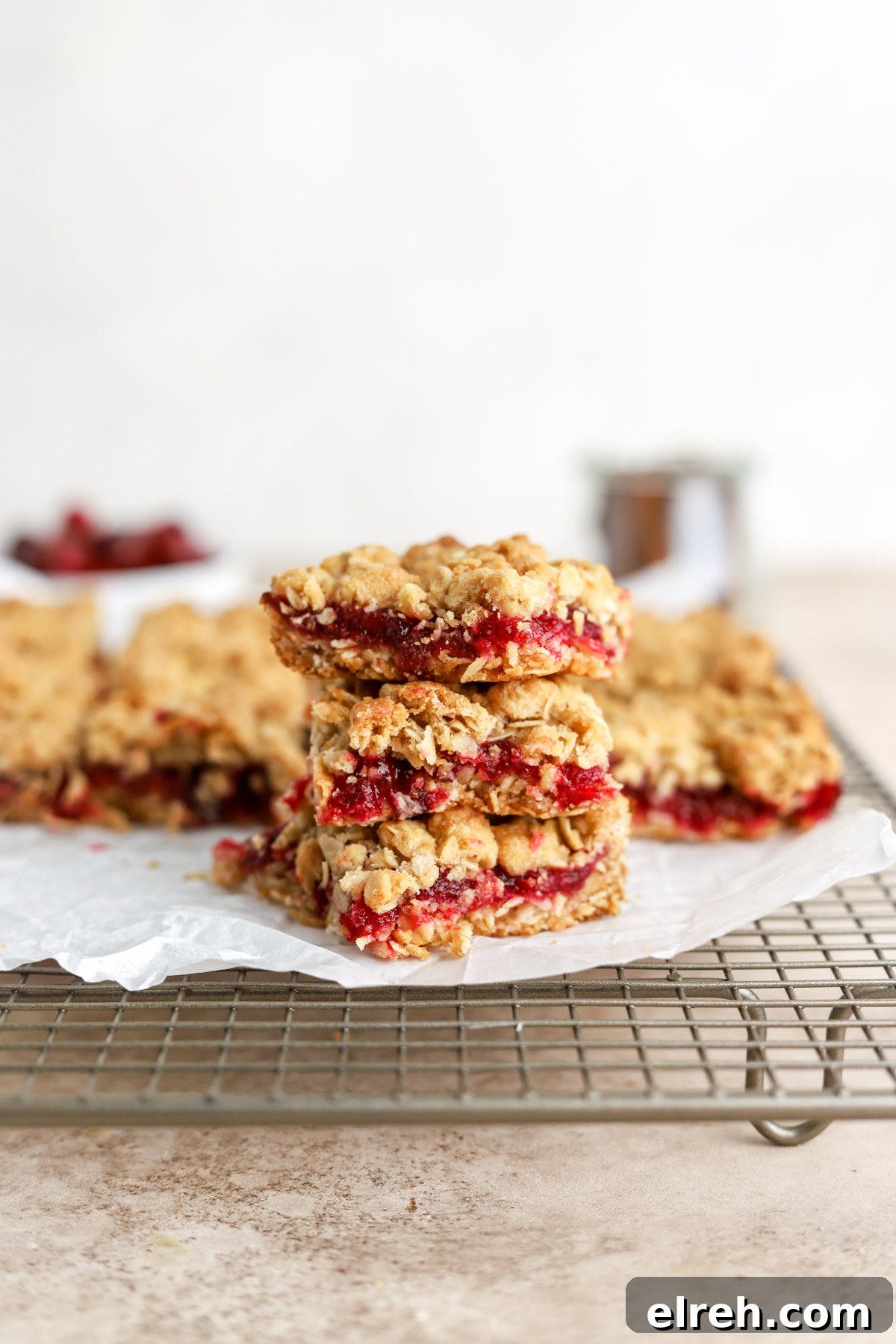 Tangy Cranberry Lemon Bars with Shortbread Crust 2 A stack of oatmeal bars filled with cranberry sauce.