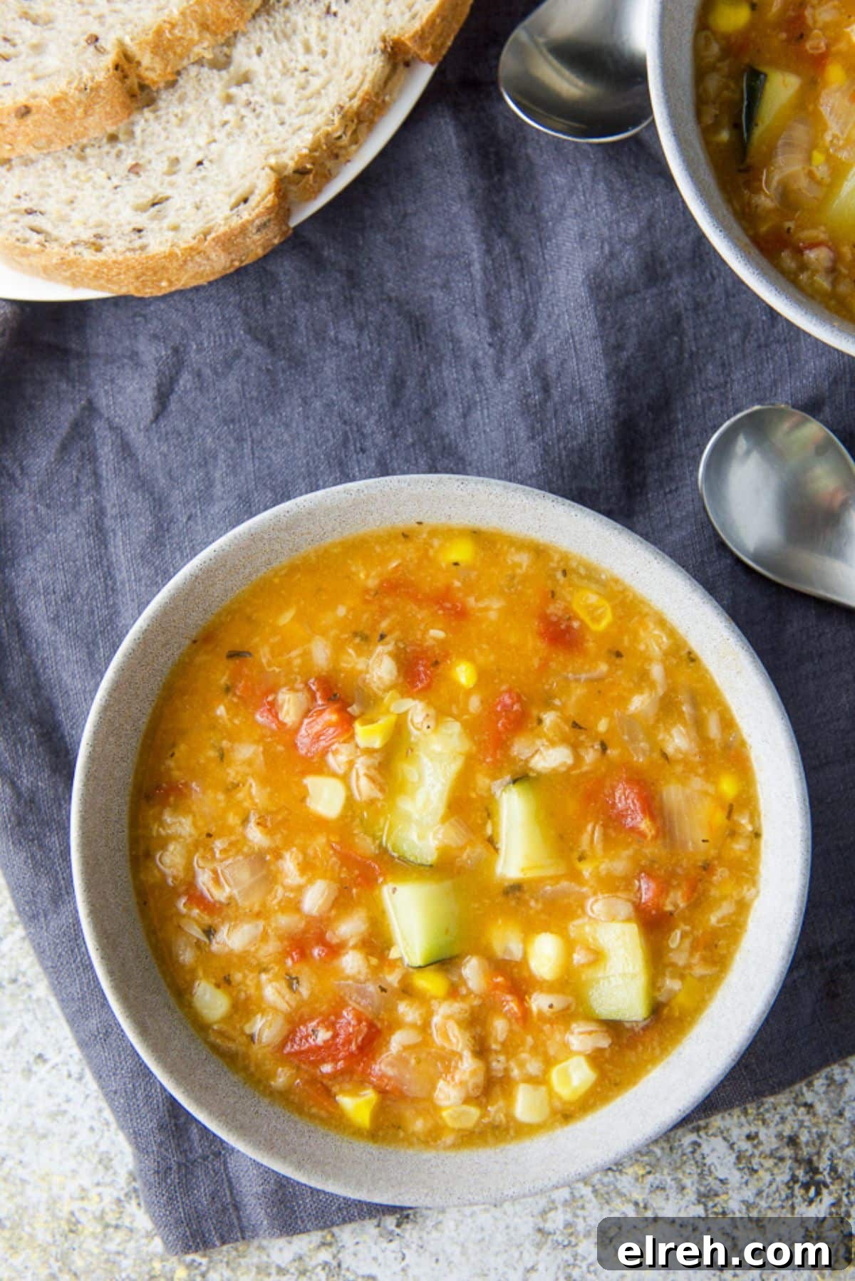 Overhead view of the soup in two bowls with two spoons and bread