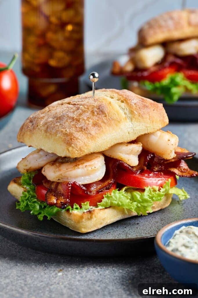 A grilled shrimp sandwich with crispy bacon on a toasted ciabatta bread