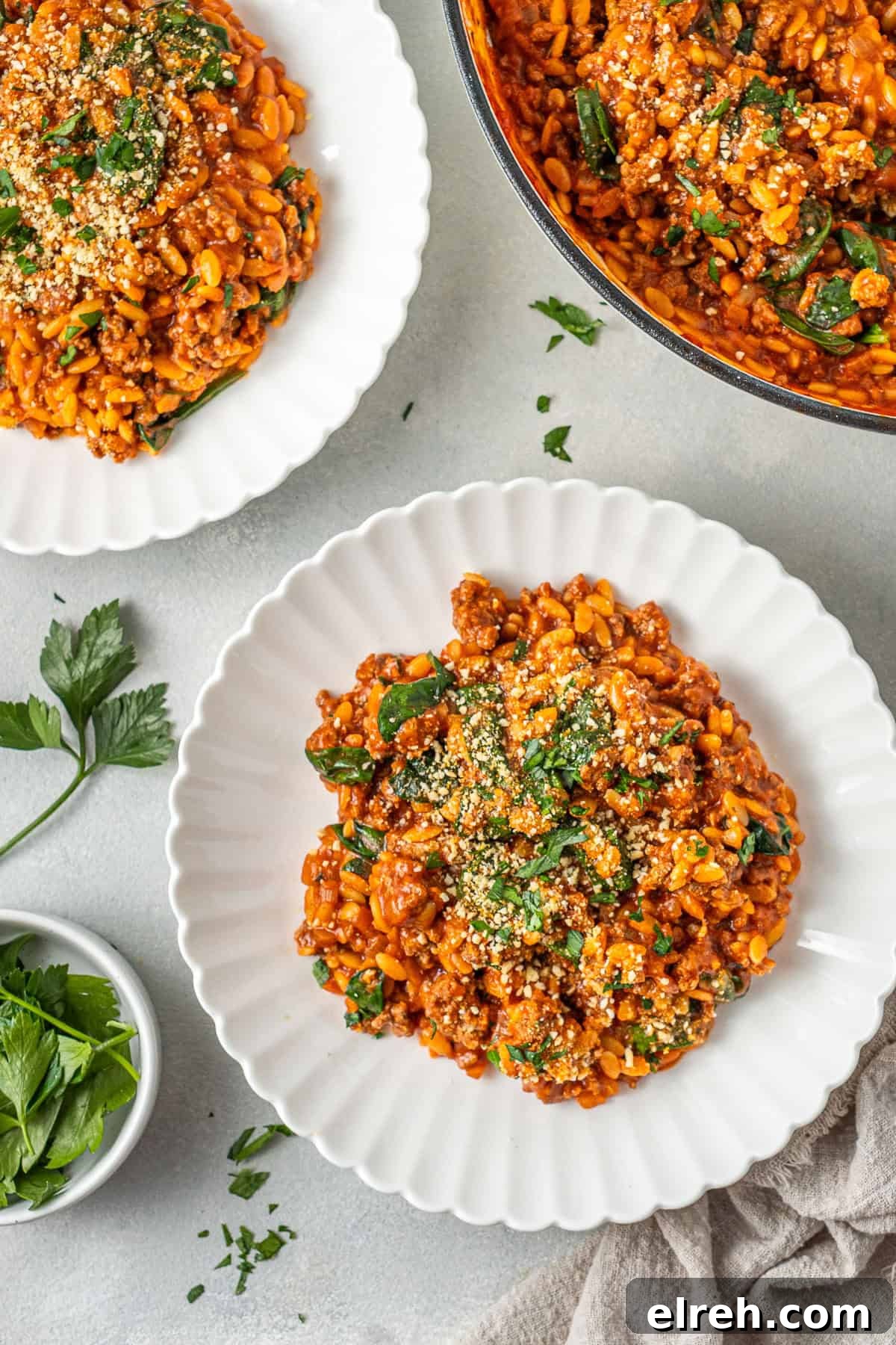 The creamy risoni and beef in white plates with parsley.