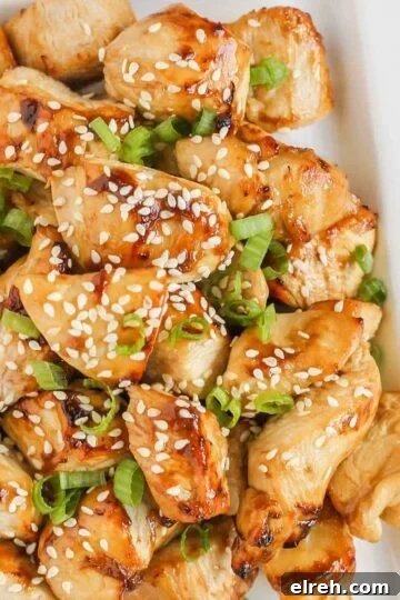 Pieces of air fried teriyaki chicken on a white plate.