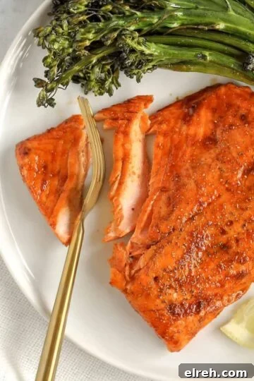 A gold fork cutting into a salmon fillet.