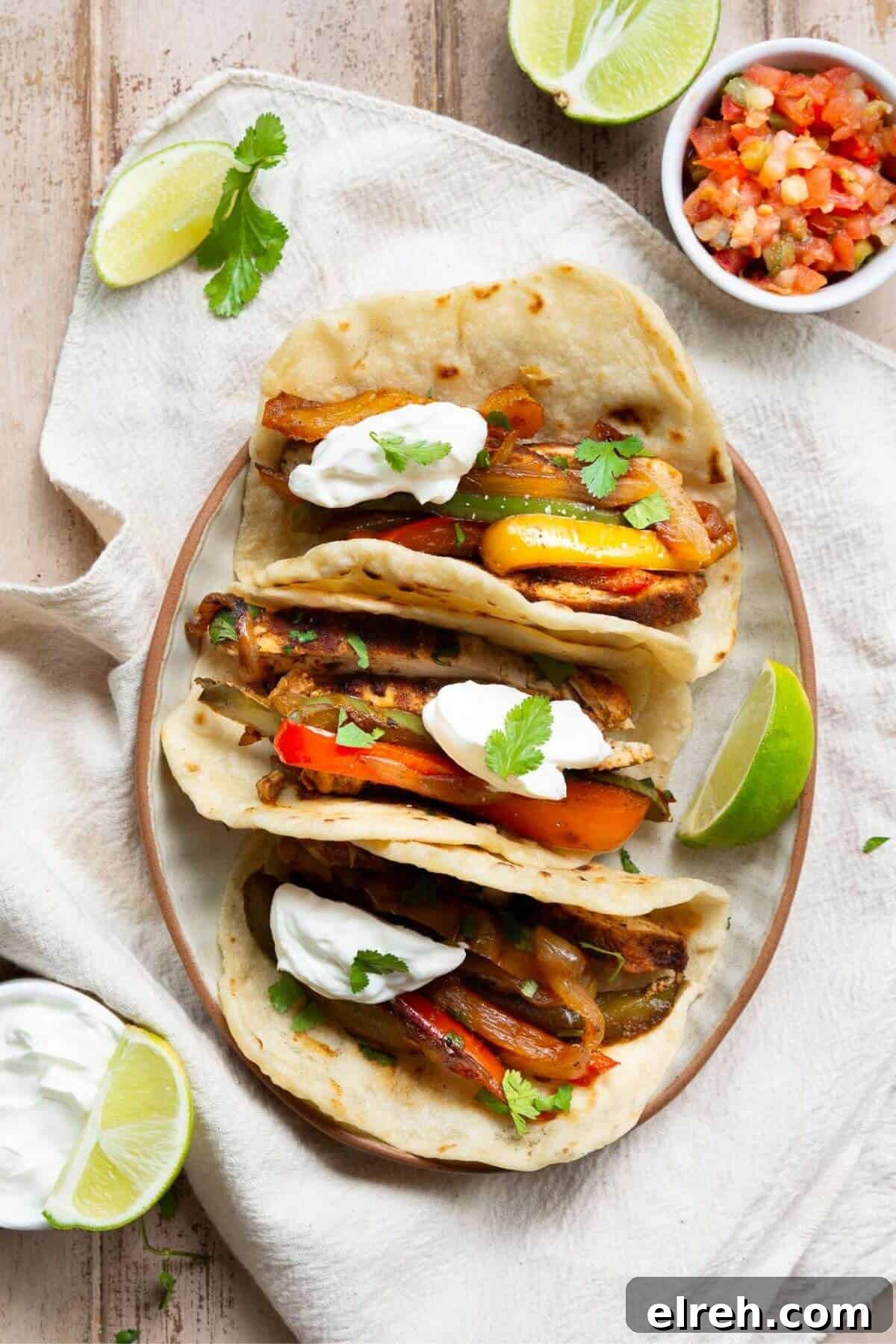 Chicken Fajita Tacos with Grilled Peppers and Onions 2 Healthy chicken fajita tacos on flour tortillas topped with cilantro, peppers, Greek yogurt, and lime.