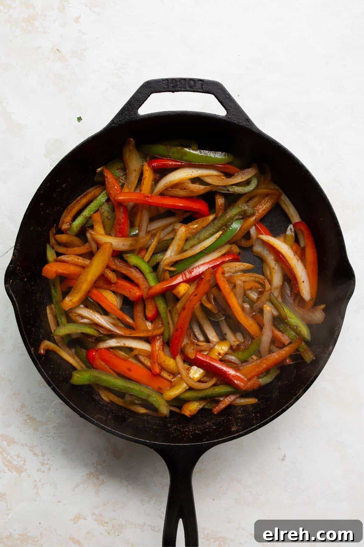 Chicken Fajita Tacos with Grilled Peppers and Onions 7 Sliced bell peppers and onions cooking in a cast iron skillet.