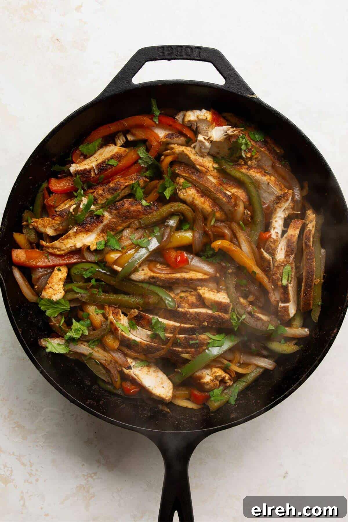 Chicken Fajita Tacos with Grilled Peppers and Onions 9 Finished chicken fajita filling with sliced chicken, peppers, and cilantro in a skillet.