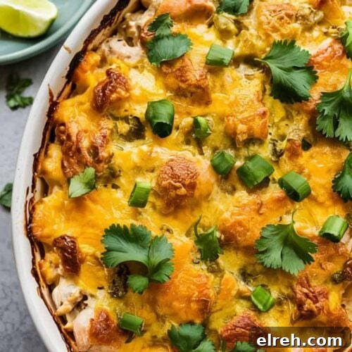 A top-down view of a Mexican-style chicken casserole in a white ceramic oval baking dish.